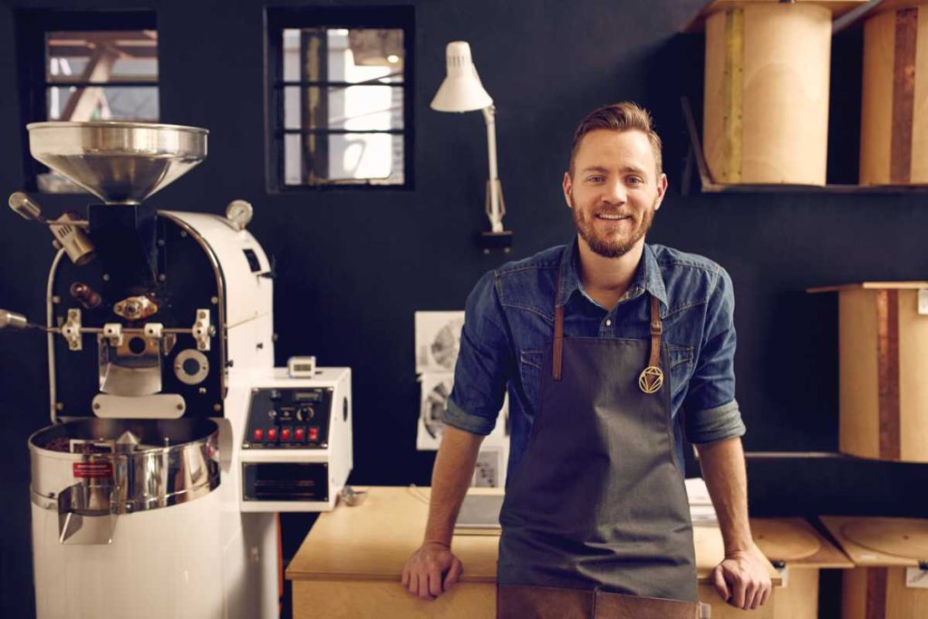 Male Entrepreneur standing in front of some wood tubes and a machine.