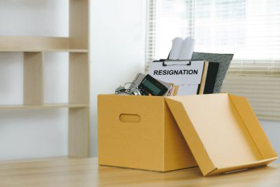 Resignation letter in cardboard box on office desk representing the cost of a bad executive hire