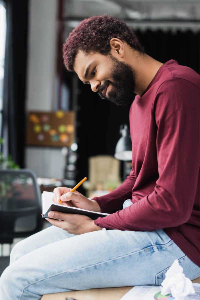 Young professional reading a notebook and smiling at his desk on his first day at work