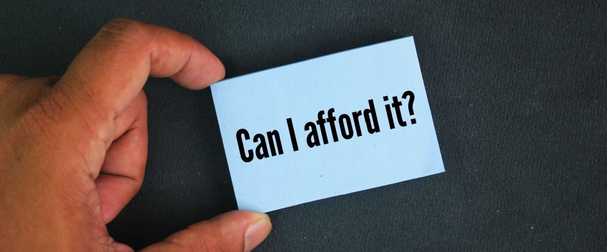 Hand holding a card that reads "Can I afford it?" representing the real cost of executive search