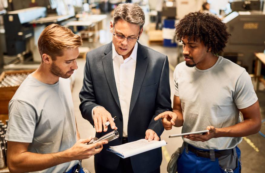 Manufacturing Executive Recruiters Content Metal fabrication team reviewing production specifications with hands-on plant leadership